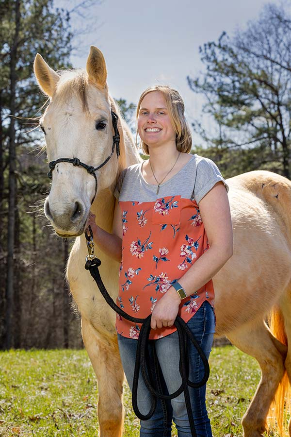 Photo of Lauren Christian standing beside horse
